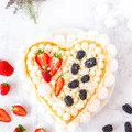 Tort biszkoptowy z kremem z białej czekolady, bezą i owocami
