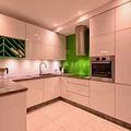 Nowoczesna biała kuchnia z soczystymi zielonymi elementami.